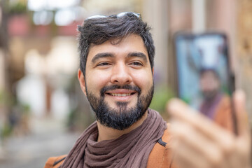 Happy young man with beard and smile at the camera taking a selfie with his phone . cheerful hipster boy university student makes a photo with his smartphone