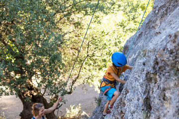 Naklejka na ściany i meble the mother will protect the baby while climbing. lesson with a trainer, children's climbing training.