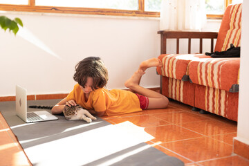 boy plays with a cat during an online lesson. home schooling.