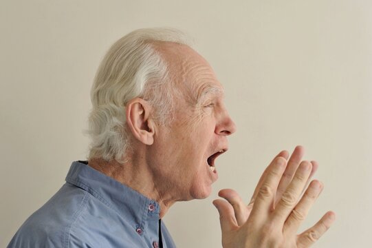 Facial portrait of an elderly gray-haired shocked furiously screaming man with an expressive look