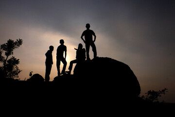 silhouette group of friendship people on a rock