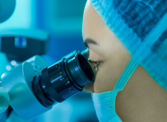 a young woman doctor looks into a microscope. the concept of eye surgery