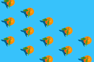 Creative pattern made of fresh orange tangerins on bright blue background. Healthy food concept. Summer refreshment theme.