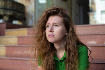 Obraz premium young beautiful woman is sitting on steps near hotel or new house, home and upset