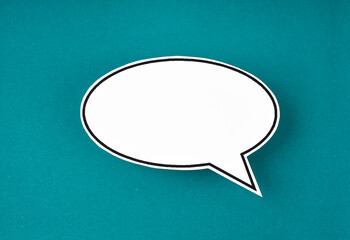 The White speech bubble shaped post it note on green background with copy space.