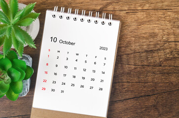 The October 2023 desk calendar for 2023 on wooden background.