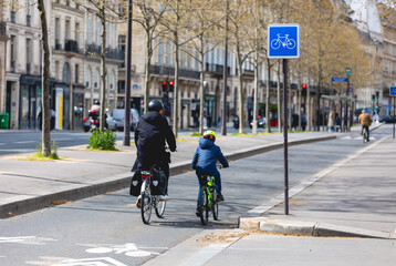 Balade à vélo avec une mère et son fils en ville.  - obrazy, fototapety, plakaty