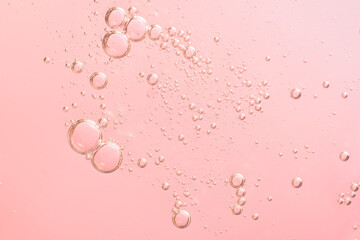 Facial serum oil surface with water bubbles. Abstract cosmetic liquid pink background for advertising and presentation of cosmetic products.