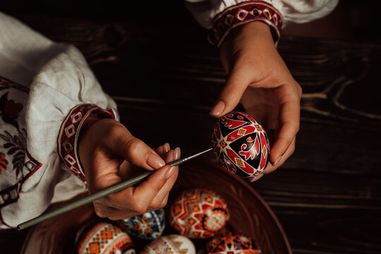 Ukrainian woman painting traditional ornamets on Easter egg - pysanka