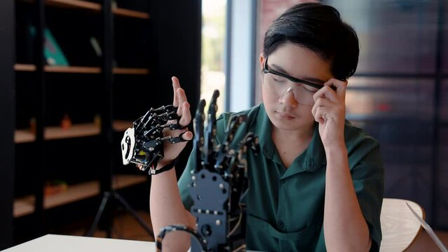 4K, Male student in technology class Wearing hand robotic controller is hand-worn device, moved hand around try control system, made stunned shocked look saw robotic hand move following moving hand.