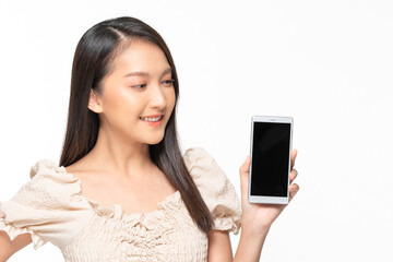 Happy attractive asian young woman smile and showing mobile phone isolated on white background. Cheerful pretty girl wear casual dress raise up smartphone to empty space for mockup to display product