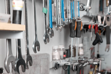 Set of wrenches of different sizes is neatly hung in a row on a special shelf in the repair shop. Close-up of a professional set of wrenches and screwdrivers in a garage workshop