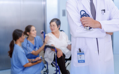 Close up focus hands of professional asian male doctor standing wearing white coat and pool medical team background.