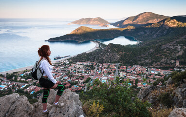 Hiking on Lycian way trail. Young girl with backpack enjoy view of Oludeniz beach and Blue Lagoon from Lycian way trail. Mediterranean coast. Fethiye. Turkey.