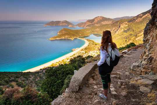 Hiking on Lycian way trail. Young girl with backpack enjoy view of Oludeniz beach and Blue Lagoon from Lycian way trail. Mediterranean coast. Fethiye. Turkey.