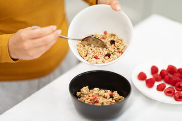 Female hands making breakfast healthy granola at home, cropped