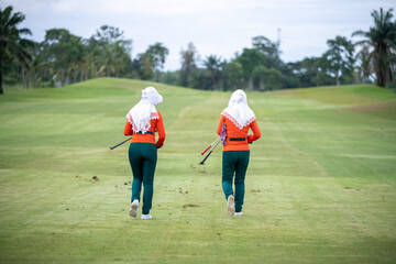 Caddies working at golf course by clear hole on green grass after finish golfer teeing in compettion game.	