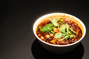 close up one bowl of Hot and sour noodles on dark background. Chinese Sichuan cuisine