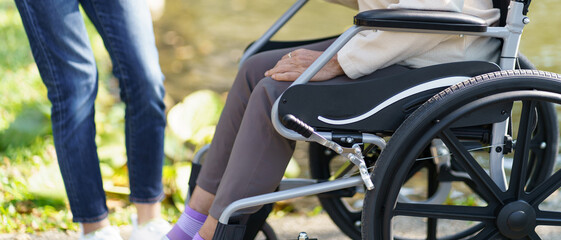 Obraz premium Nursing home. Young caregiver helping senior woman in wheelchair.