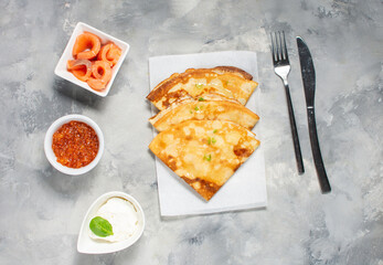 Russian thin pancakes or blini with red caviar nd salmon on concrete table. Top view
