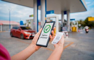Woman using contactless payment by mobile phone with QR code at car filling station