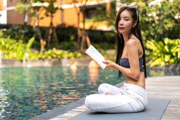 Portrait of beauty asian woman read the paper book work study and looking at page magazine while sitting in swimming pool on summer, travel, vacation,  holiday, rest, relax at resort spa