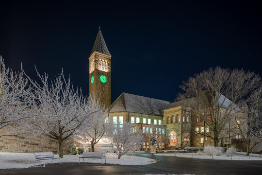 Ithaca, New York, US - March 29, 2023: Night photo of McGraw clock tower with non typical green clock face in anticipation of Dragon Day.  The tower is a distinctive landmark in Cornell University