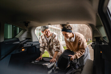 two women mother and daughter pack luggage baggage in trunk of the car - obrazy, fototapety, plakaty