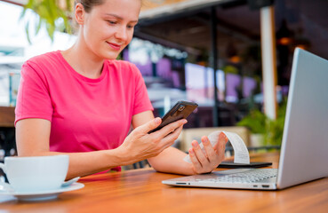 Woman using contactless payment by mobile phone with QR code at cafe