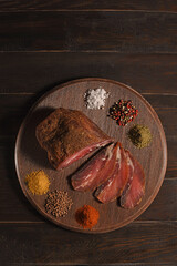 Dried Processed Beef Jerky with spices on wooden board against dark background. Slicing. Top above,...