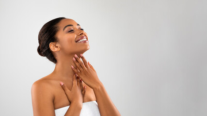 Joyful black woman touching her soft flawless skin on neck