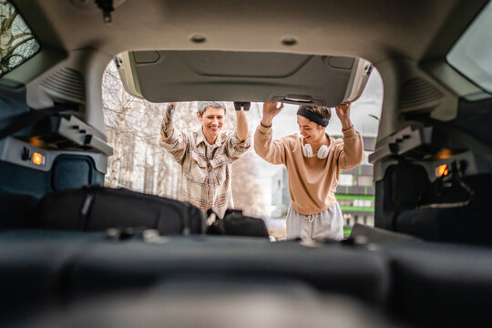 two women mother and daughter pack luggage baggage in trunk of the car - Powered by Adobe
