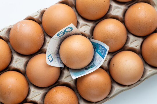 Eggs getting more expensive in Poland. The concept of rising inflation, 50 zloty banknote sticking out from under the tray with eggs