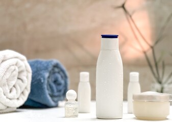 Closeup of toiletries bathroom setup in a isolated white tiles background with copy space for inscription. Towl, dispensers, comb, toothbrush and moisturizer. Bathroom interior. 