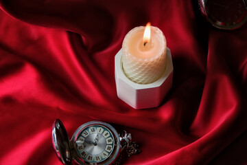 White burning candle on a red background with an old pocket watch, postcard on a blue background. Table decor for a festive dinner, Witchcraft, esoteric spiritual ritual. autumn equinox festival