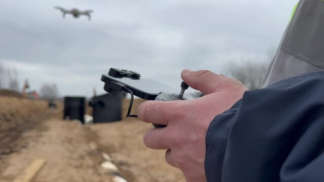 Geodesic quadcopter. A human surveyor. Launching a quadcopter over a construction site. The surveyor launches the drone. Geodetic works before construction. A surveyor in a protective helmet is sent o