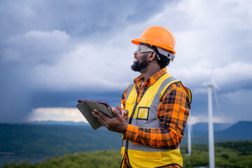 Obraz premium Portrait of engineer African American man working with laptop in wind turbine farm.