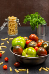 Different varieties of green and red tomatoes in a metal can. Pasta in a glass jar