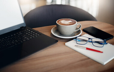 Close-up view, white cup of coffee with computer laptop, notebook, pen and eye glasses on wooden table in cafe, People resting after work in a calm cafe