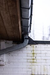 A portrait of a broken metal drain pipe connected to the gutter of a roof. The drain needs repairs...