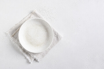 White empty plate with linen towel on white kitchen table top. Kitchen and cooking background, mock up. Top view. Copy space.