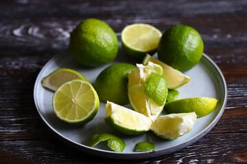 Limes and slices of limes on a dark wooden background.