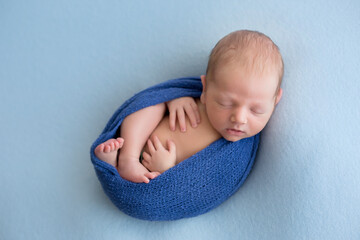 sleeping newborn in a wrap. baby on a blue background
