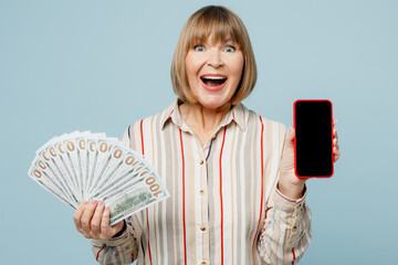 Elderly fun woman 50s years old wear light striped shirt hold in hand fan of cash money in dollar...