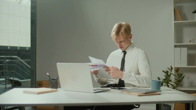 Engineer Bursting with Joy Reviewing Documents. Successful Man Making Profitable Deal and Celebrating the End of the Project.Young Smiling Architect Scatterring Papers around Him Waving Fists Happily