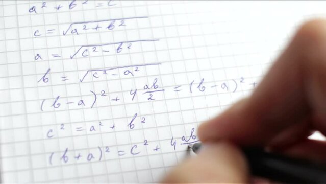 A student writing down math formulas in a notebook
