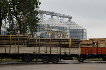 cargo trucks, transporting logging timber. with grain silos in the background © Lautaro