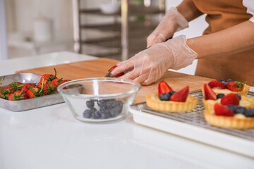 Woman decorating bakery with berries.