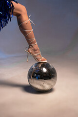 Female leg in beautiful white sandals on a disco ball