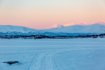 Fototapeta na wymiar Abisko in Lapponia in Svezia. Tramonto al lago di Tornetrask ghiacciato. Sole, neve, ghiaccio, al circolo polare artico, un paesaggio del nord Europa